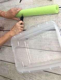 a person is using a large green tool to paint the side of a wooden table