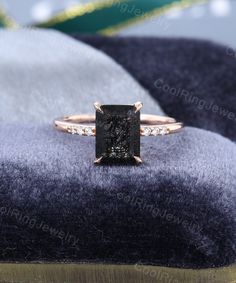 an engagement ring with a black diamond in the center on top of a velvet cushion