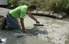 a man is laying tile on the ground and working with his hands to fix it