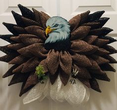 a wreath with an eagle on it is hanging on the front door to give as decoration