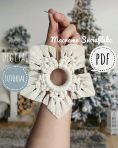 a hand holding a white crochet snowflake ornament in front of a christmas tree