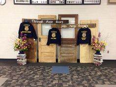 two police shirts on display in front of a door with flowers and books around it