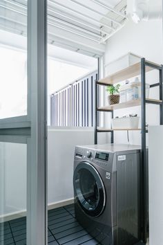 a washer and dryer in a room with open shelving on the wall