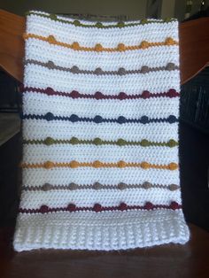 a crocheted blanket sitting on top of a wooden chair