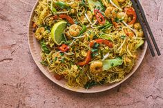 a plate full of noodles and shrimp with chopsticks