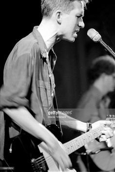 a man playing guitar while singing into a microphone