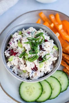 a white plate topped with cucumbers and carrots next to a bowl of chicken salad