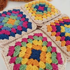 four crocheted coasters on a table with a teddy bear in the background