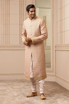 Salmon and gold digital-printed sherwani with aari, zardozi embroidery and features a gold embroidered collar, cuffs and hemline. Paired with a salmon kurta and churidar.
Components:3
Pattern:Printed,Embroidered
Type of Work:Aari, Zardozi
Neckline:Mandarin
Sleeve Length:Full Sleeves 
Fabric:Sherwani: Silk Dupion, Kurta: Katan Silk, Churidar: Poplin Lycra
Color:Peach
Other Details:
Placement embroidery
Front buttons
Digital print
Occasion:Wedding - Aza Fashions Peach Sherwani, Gold Sherwani, Embroidered Sherwani, Zardosi Embroidery, Sherwani Groom, Mens Sherwani, Zardozi Embroidery, Wedding Sherwani, Tarun Tahiliani