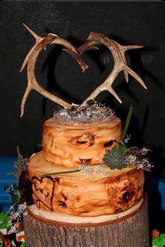 a cake with deer antlers on top of it sitting on a tree stump in the shape of a heart