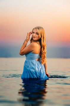 a woman standing in the water with her hands on her head and looking off into the distance