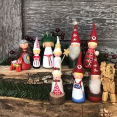 a group of christmas gnomes sitting on top of a wooden shelf next to pine cones