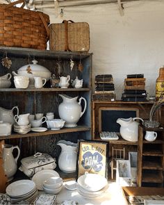 an assortment of white dishes and bowls on display in a room filled with wooden shelves