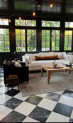 a living room with black and white checkered flooring, two couches and coffee table