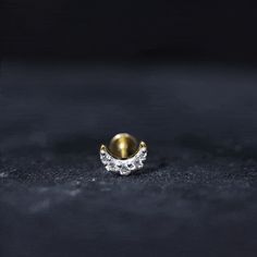 a gold and diamond ring sitting on top of a black surface