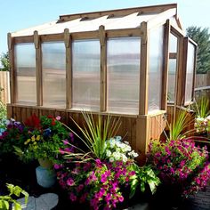 a small wooden structure surrounded by flowers and plants