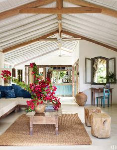 a living room filled with lots of furniture and flowers in vases on the coffee table