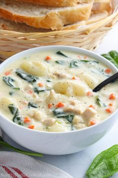 a bowl of soup with bread in the background