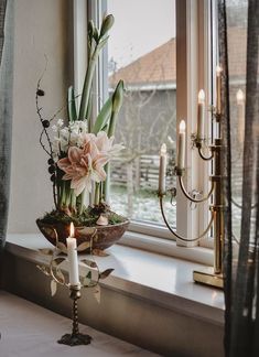 a vase filled with flowers sitting on top of a window sill next to a candle