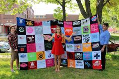 three people standing in front of a large quilt made out of t - shirt shirts