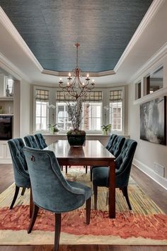 a dining room table with blue chairs and a chandelier hanging from the ceiling