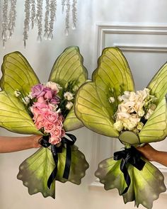 two hands holding bouquets with flowers in them