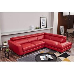 a red leather sectional sofa sitting on top of a wooden floor next to a coffee table