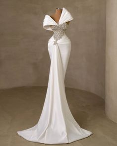 the back of a wedding dress with an open neckline and draped over it, in front of a wall