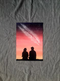 two people are sitting on a blanket looking at the stars in the sky above them