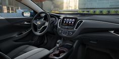 the interior of a chevrolet vehicle with dashboard, steering wheel and center console in front of buildings