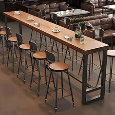 a long table with stools in front of it next to couches and tables