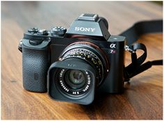 a sony camera sitting on top of a wooden table next to a black strap that has the word sony written on it