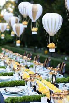 a long table is set with plates and hot air balloons in the shape of lanterns