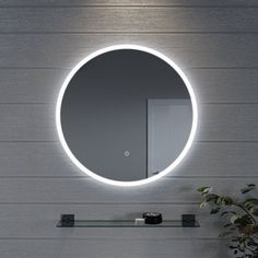 a bathroom with a round mirror on the wall next to a sink and potted plant