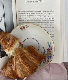 two croissants sitting on top of a plate next to an open book