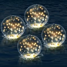 three bubbles with lights floating in the water on top of each other, and one has a small boat inside it