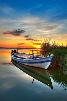 there is a boat that is sitting on the water in the lake at sunset or dawn