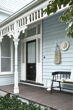 the front porch of a house with a bench and hat hanging on it's wall