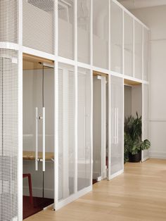 an office with white partitions and wooden flooring in the center, along with potted plants