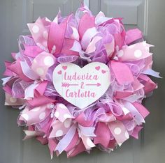 a pink and white heart wreath with polka dots on the front door for someone's wedding