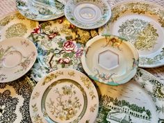 many plates are laying on the table with different designs and colors, including green flowers