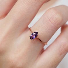 a woman's hand with a gold ring and an amethoraite stone