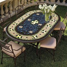 a table with chairs and a vase on it sitting in the middle of some grass