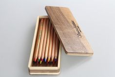 a wooden box filled with colored pencils on top of a table