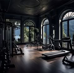 there are many exercise machines in this gym room with large windows overlooking the water and mountains