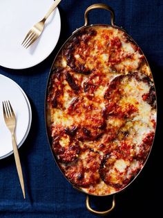 a pizza sitting on top of a pan next to two plates with forks and spoons