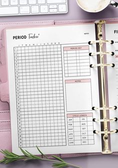 a pink planner with the words period tracker written on it next to a cup of coffee