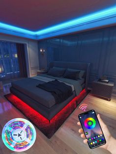 a person holding a cell phone in front of a bed with colorful lights on it