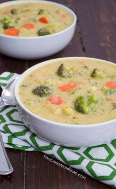 two white bowls filled with broccoli and carrots on top of a table