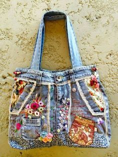 an old jean purse hanging on the side of a wall with patches and flowers all over it